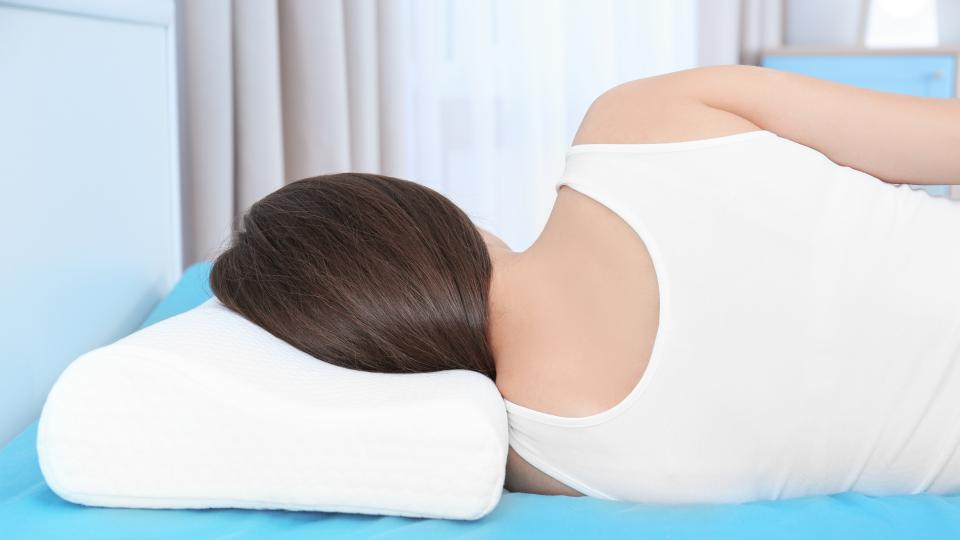 A woman lying on her back with a pillow supporting her head.