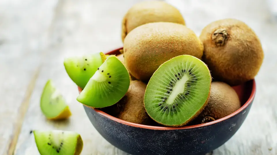 Fresh kiwi fruit in a bowl on a wooden table