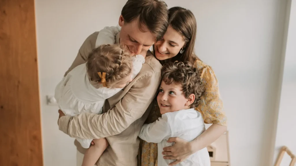 A happy family embraces tightly in a cozy room.