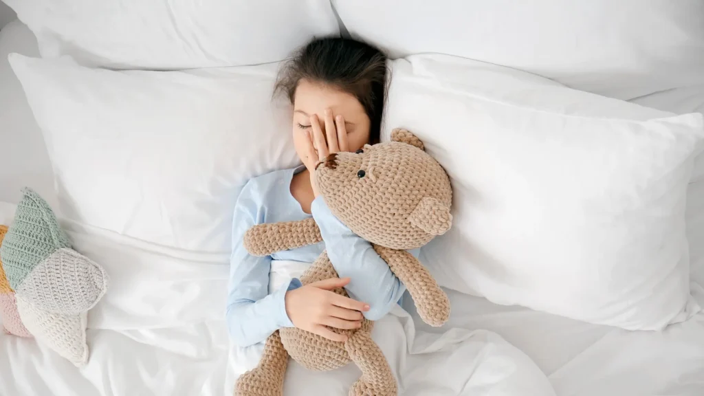 A young girl peacefully sleeps in bed next to her favorite teddy bear. Common sleep disorders