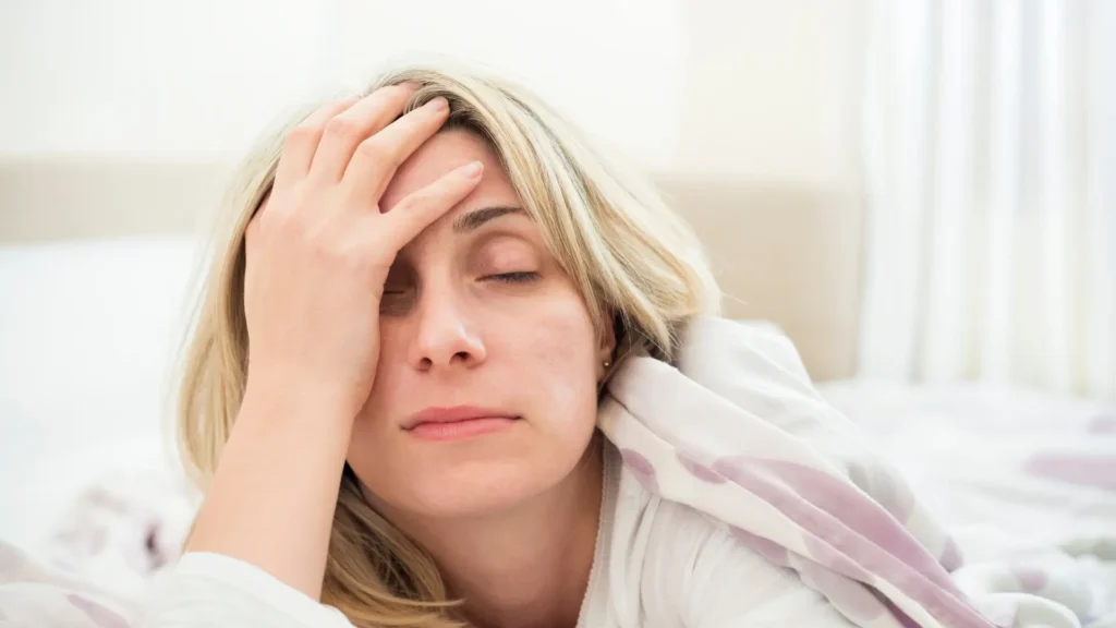 A woman peacefully rests in bed, her head gently resting on the soft pillow, enjoying a moment of relaxation and tranquility.