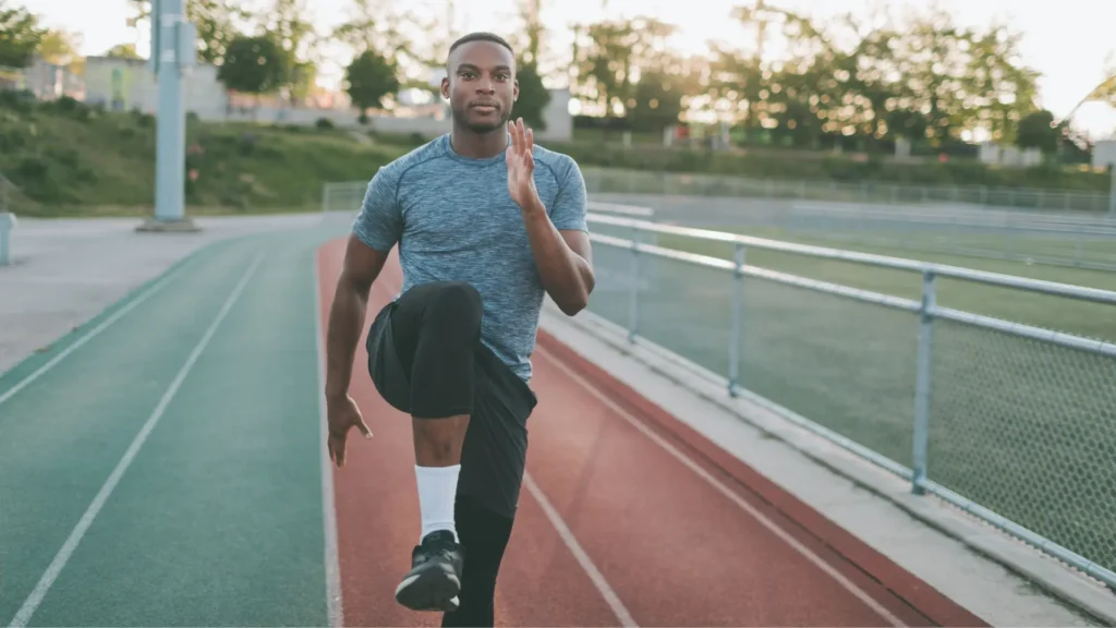 A man stretching on a running track, preparing for a workout.