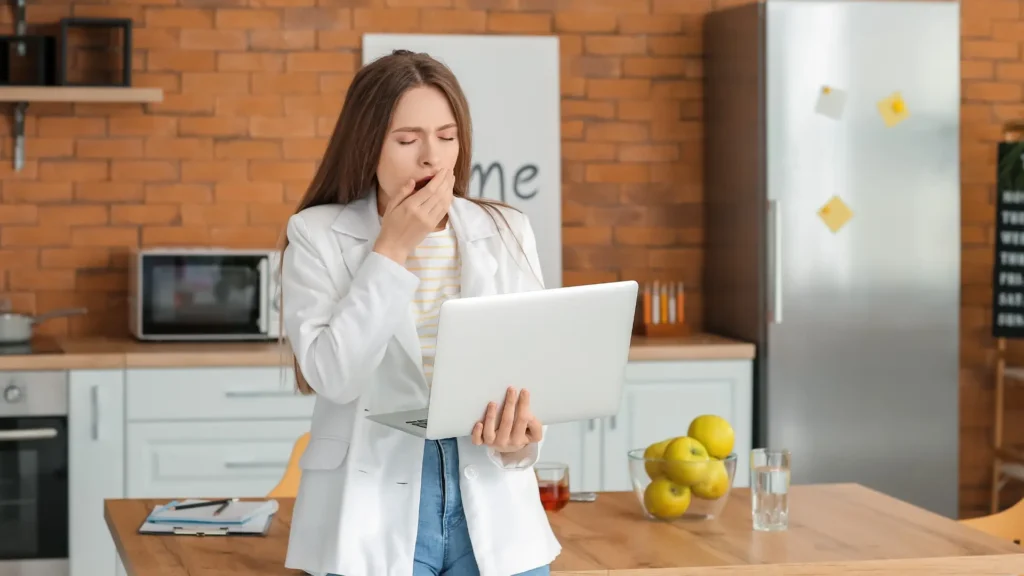 Woman worried expression, hand over mouth, staring at laptop.