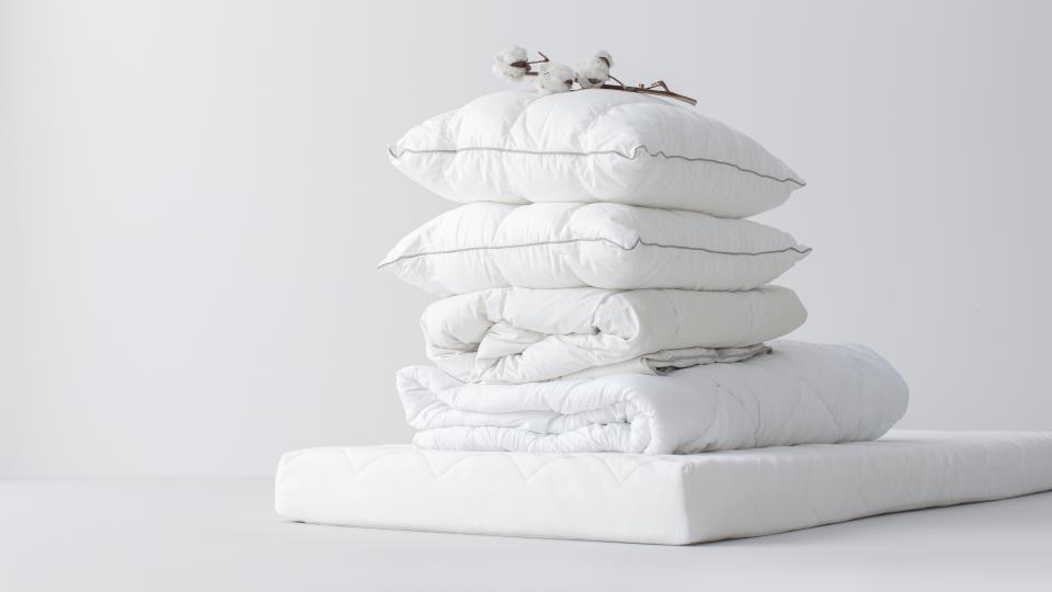 White pillows stacked neatly on a white surface.