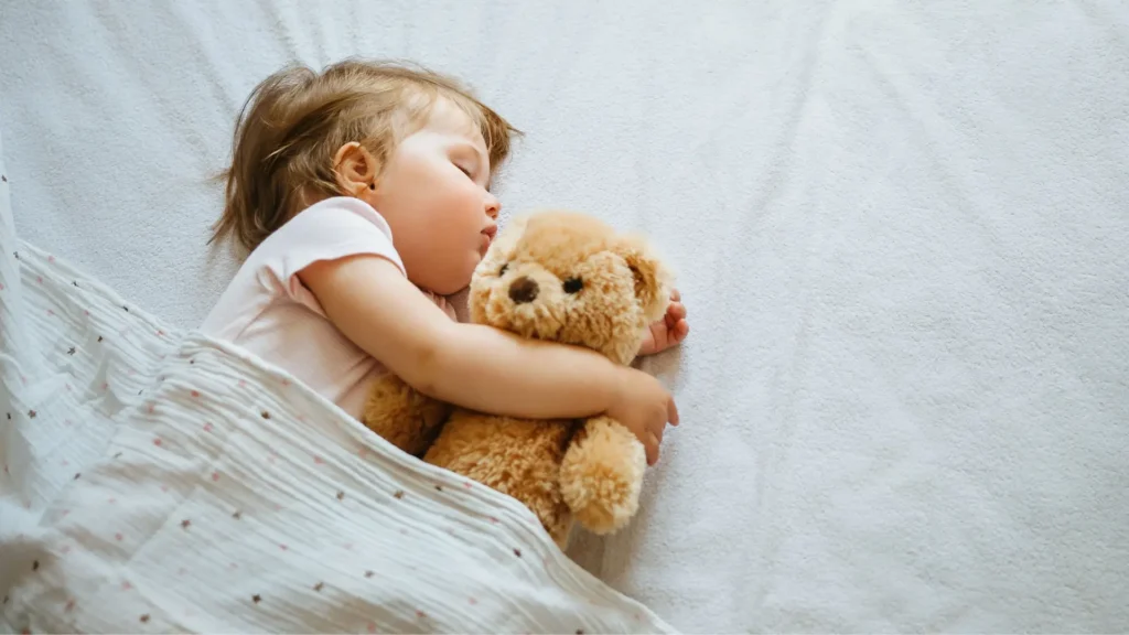 A peaceful baby sleeping soundly next to a teddy bear.