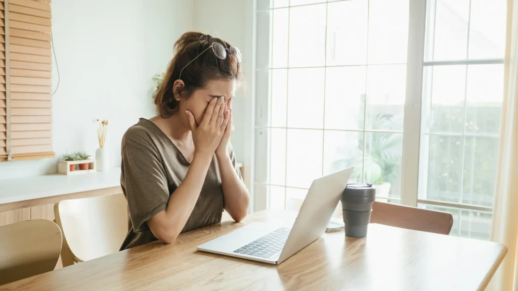 A woman sitting at a table, focused on her laptop.